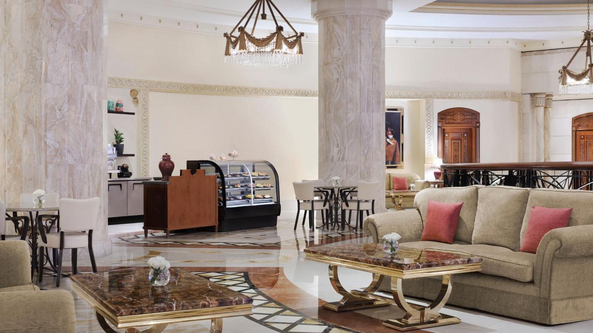 Intercontinental Dar Al Iman Madinah By Ihg Hotel Medina Buitenkant foto The photo shows a luxurious hotel lobby or lounge area. It features elegant marble floors and tall columns. There are comfortable seating arrangements with a sofa and stylish tables that have marble tops. A display case for pastries or refreshments i