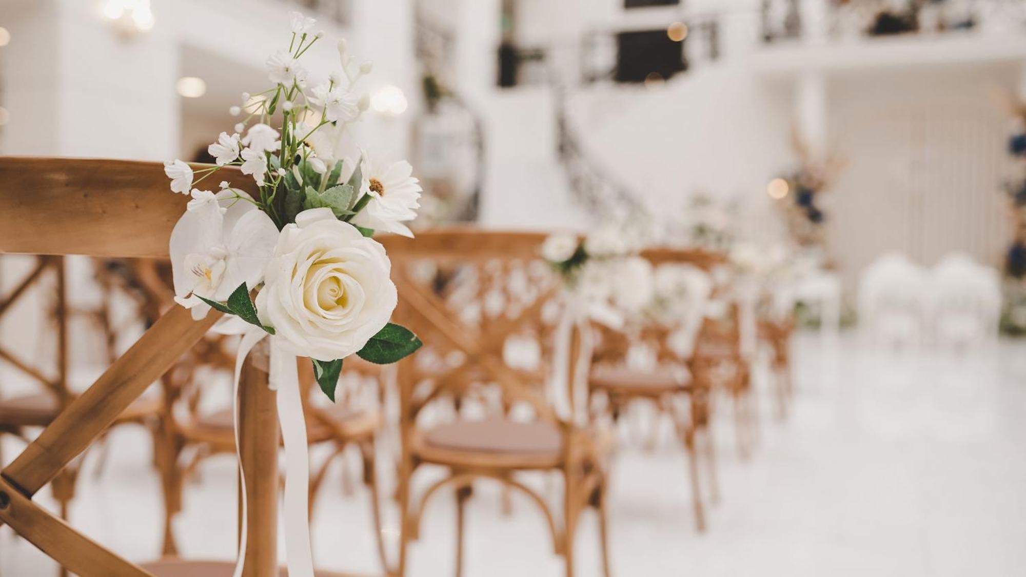 Intercontinental Dar Al Iman Madinah By Ihg Hotel Medina Buitenkant foto The photo showcases a beautifully arranged event space, likely set up for a wedding or special occasion. In the foreground, wooden chairs are neatly lined up, some adorned with decorative floral arrangements. The flowers include white roses and small