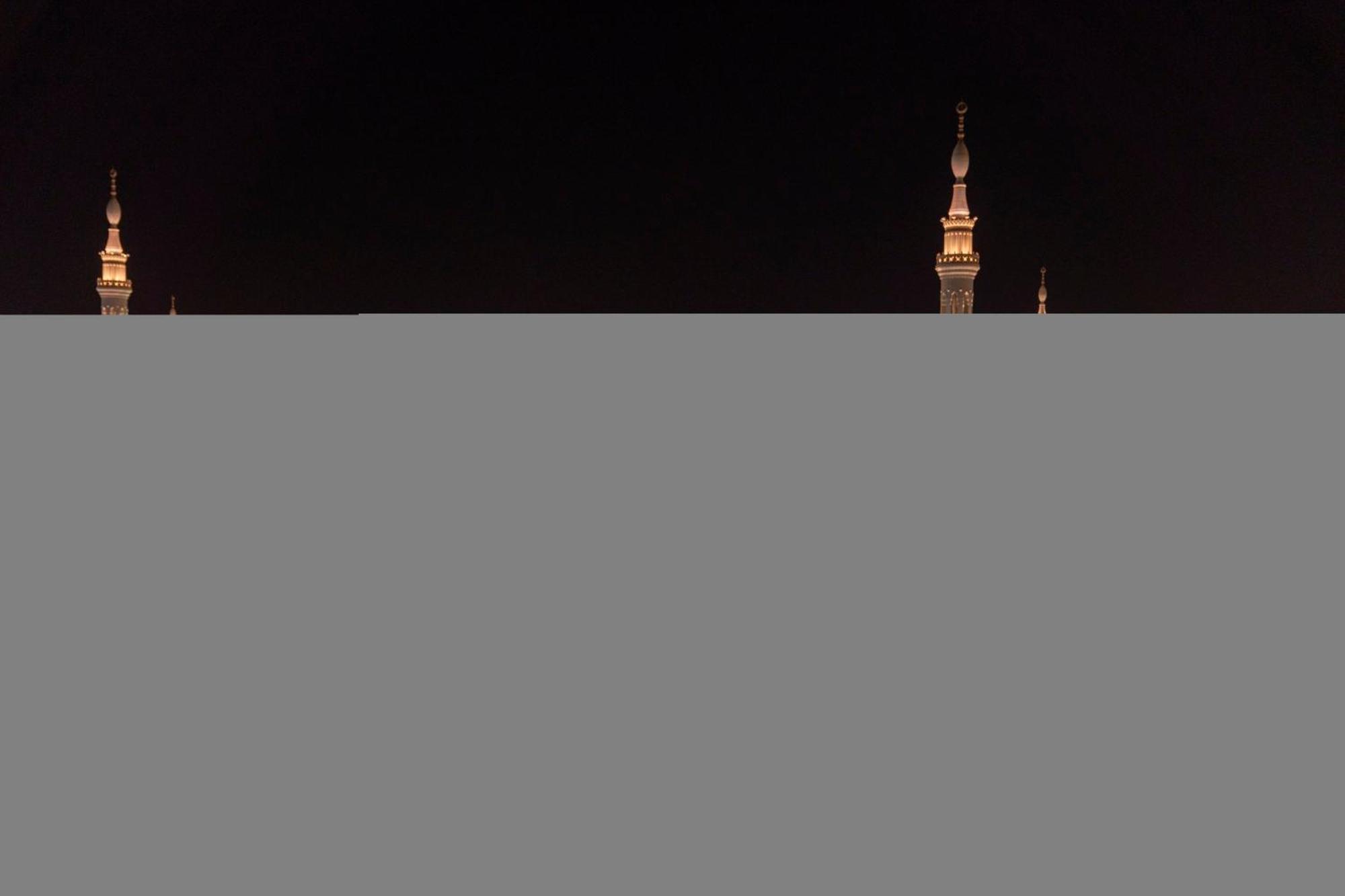 Intercontinental Dar Al Iman Madinah By Ihg Hotel Medina Buitenkant foto The image appears to show a night scene featuring tall structures with pointed tops, likely minarets, illuminated against a dark background. The lighting creates a striking contrast, highlighting the architectural details of the structures. The overa